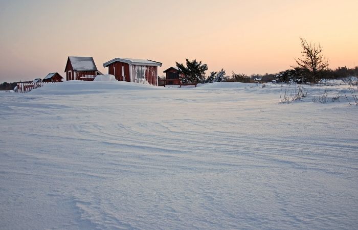 a lanscape image of snow with a bran in the background