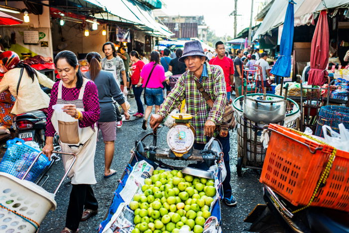 Environment portrait of a man selling apples in a market street in Chiang Mai 