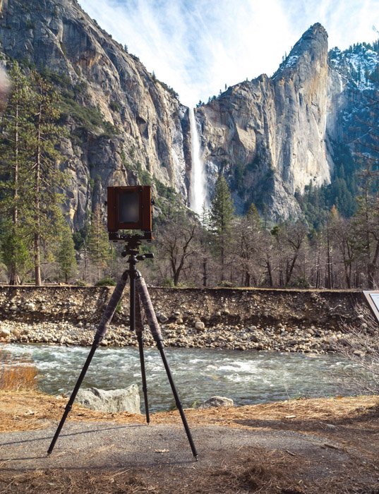 film camera in front of a mountain scene with a waterfall