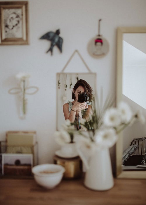 photographer shooting an image of her reflection in a small mirror