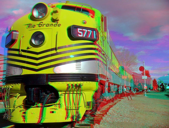 3D anaglyph photo of the front of a yellow train and its cars on tracks