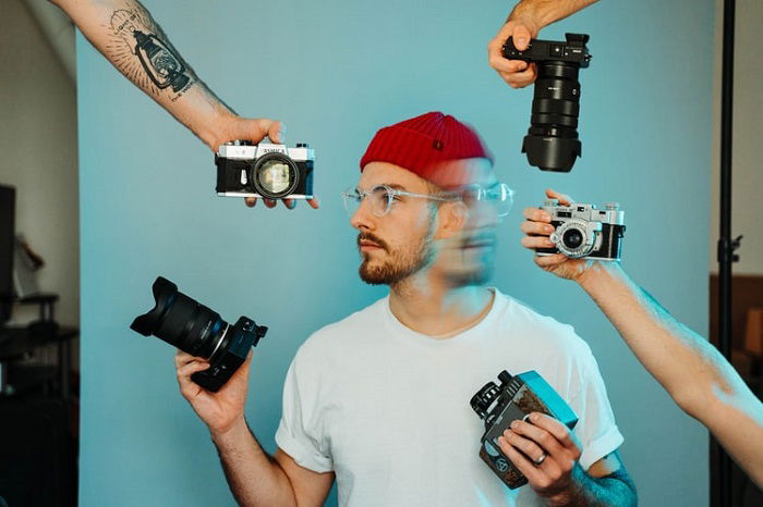 double exposure image of a model in a studio with several cameras held around him