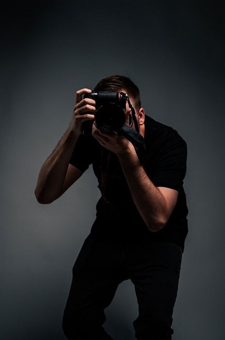 photographer facing the camera with a dark grey background