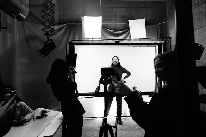 black and white photo of a female model posing in a studio in front of a photographer