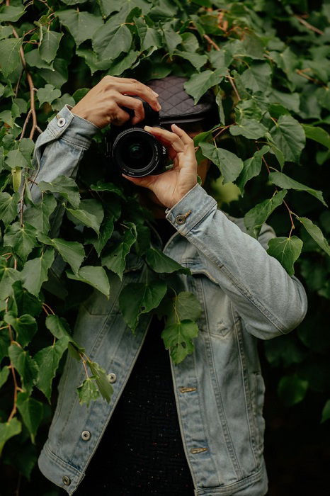 image of a photographer facing the camera while under leaves