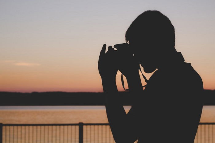 photographer looking out over a body of water at sunset