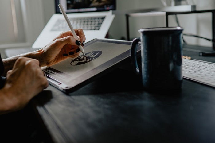 graphic designer working on a tablet with a stylus and a cup of coffee in the foreground