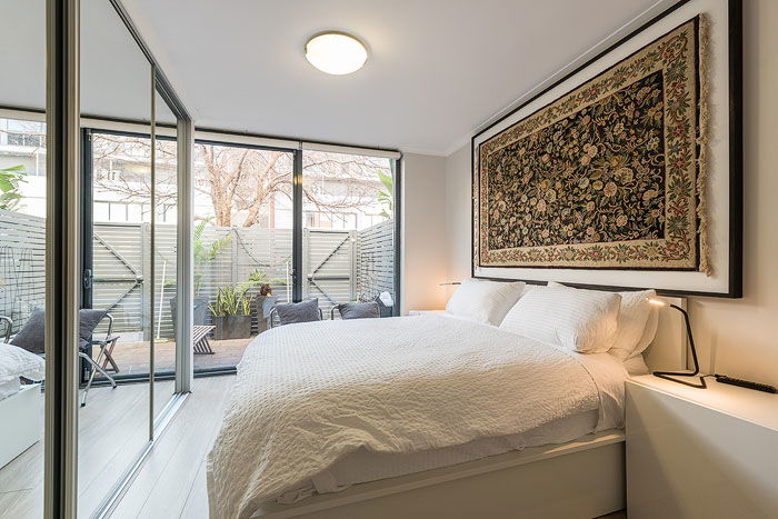 Interior of a bedroom with a closet mirror and large windows shot for how to get into real estate photography