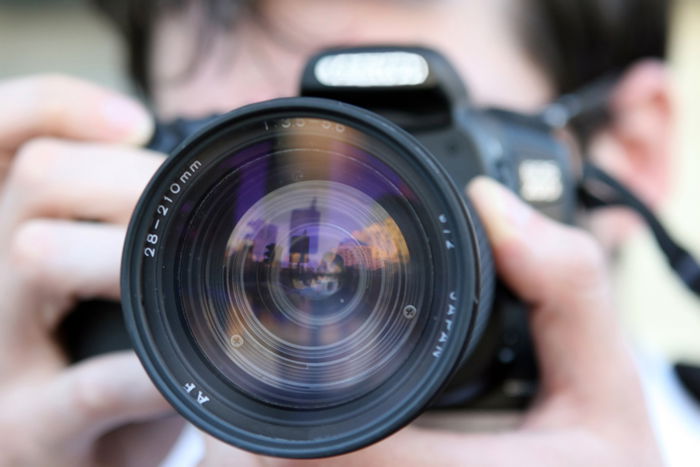 A person looking through a camera lens with lens elements