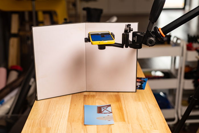 A smartphone on a stand to scan a photo on a table below