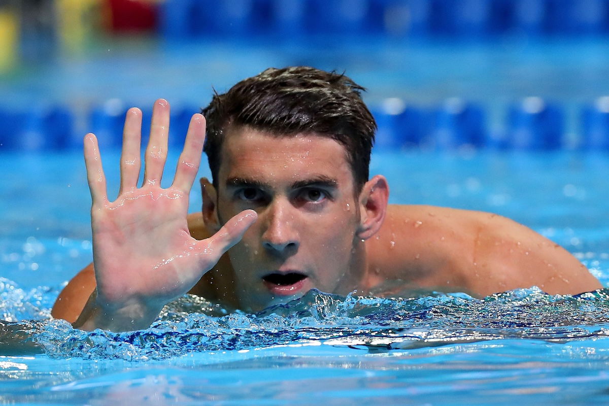 A close-up of a swimmer in a pool waving taken by one of the best sports photographers Tom Pennington