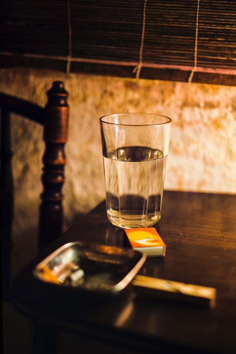 A glass of water on a table shot by candlelight