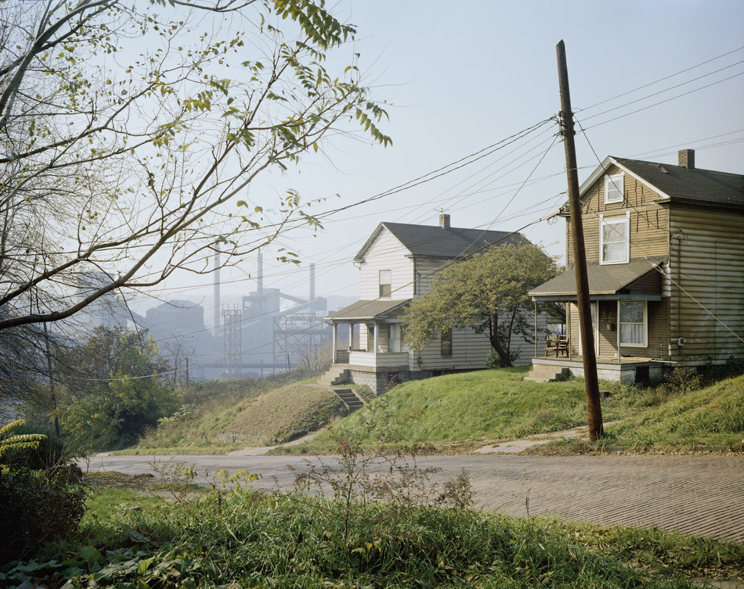 two quaint houses in front of an industrial setting