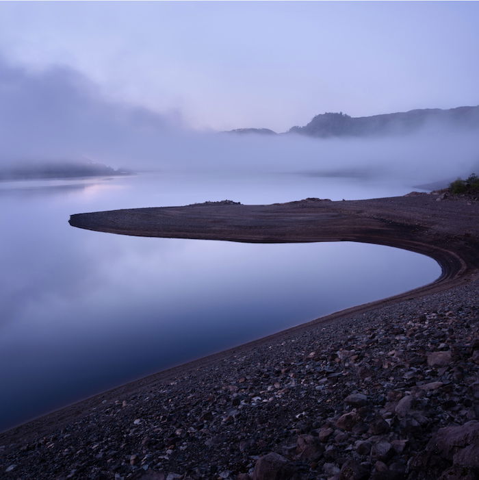 landscape photography: a layer of fog floats above a rocky shoreline