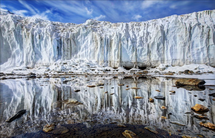 impressive landscape photography: face of a glacier mirrored on still water