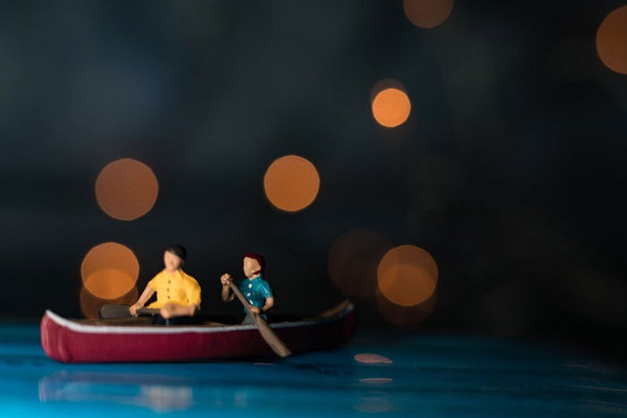 miniature photography of two people in a canoe