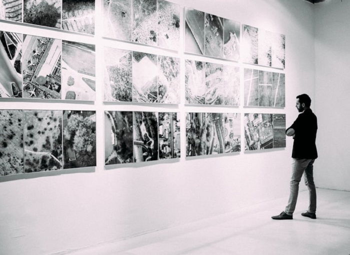 black and white image of a man viewing images in a gallery