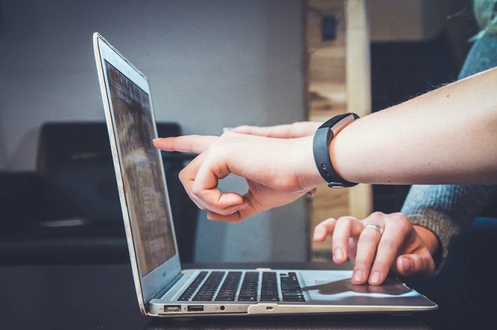 person pointing to a macbook screen