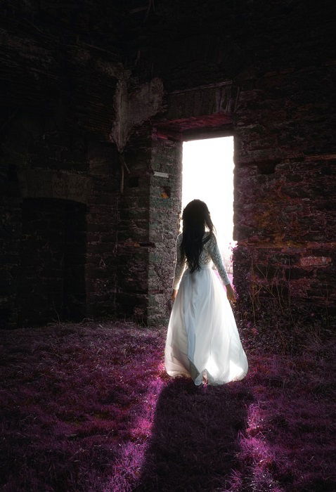 girl walking towards a bright stone door