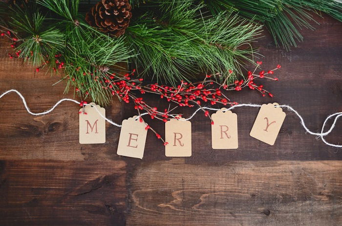 Christmas flat lay with pine cone branches berries and merry written out on cards