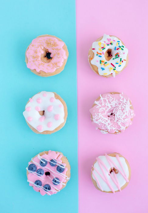 flat lay background idea: six donuts laid on top of a blue and pink flat lay background