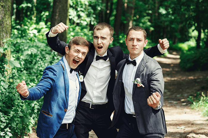 groomsmen photo idea: Funny hero pose by three groomsmen 