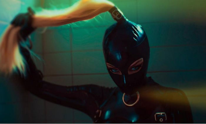 horror photography inspiration: woman in a latex hood holds her ponytail with her latex-gloved hand