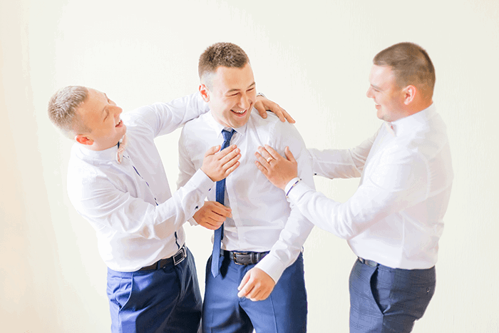 a photo of three groomsmen laughing together