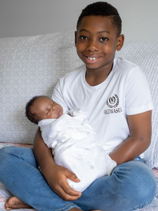 photo ideas for siblings: young child sitting with their newborn sibling