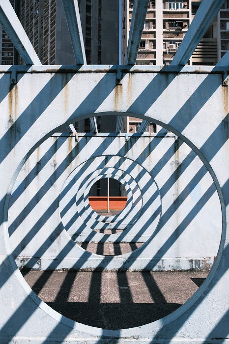 rhythm in photography: a shot taken through repeating circular holes while shadows from bars create an alternative rhythm 