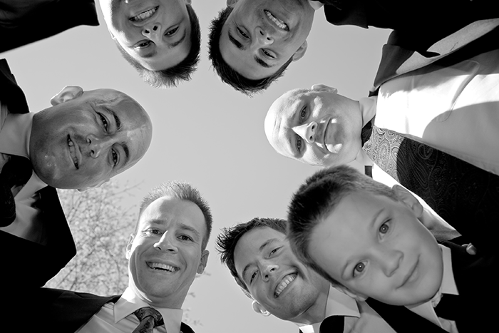 groomsmen photo idea: a black and white image looking up at circle of groomsmen