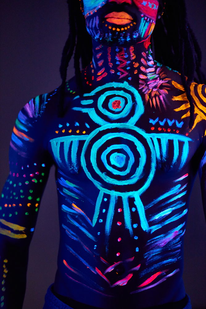 black light photography tips: a man with UV paint on his face and torso shot in black light