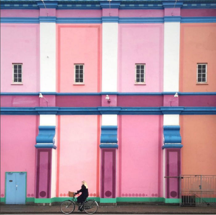 A woman is riding a bike past a colorful building.