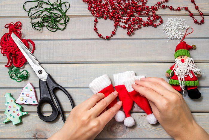 Christmas flat lay of materials and a person making handmade Santa decorations