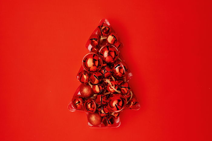 Christmas flat lay with tree made from jingle bells on red background