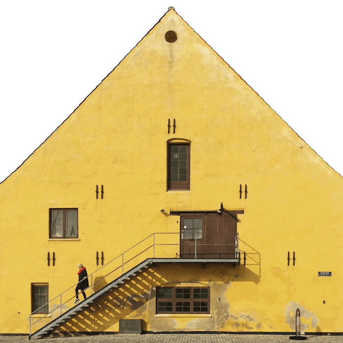 city photography: A person walking down a staircase in front of a large yellow building