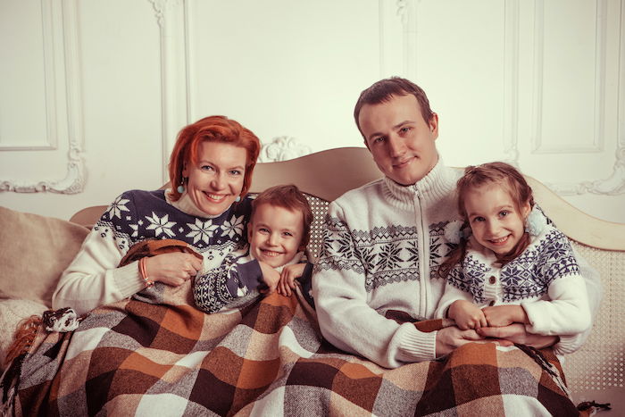 Family under a blanket and in wool sweaters for Christmas card photo ideas