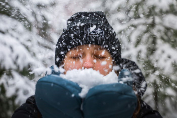 Person blowing snow in their hands for Christmas card photo ideas