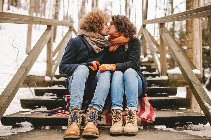 a couple kisses as they sit on the stairs 