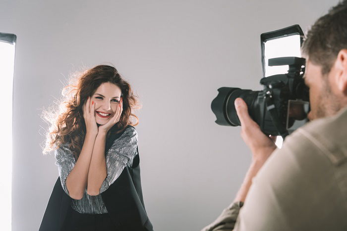 a woman poses with her hands on her face while getting her portrait taken