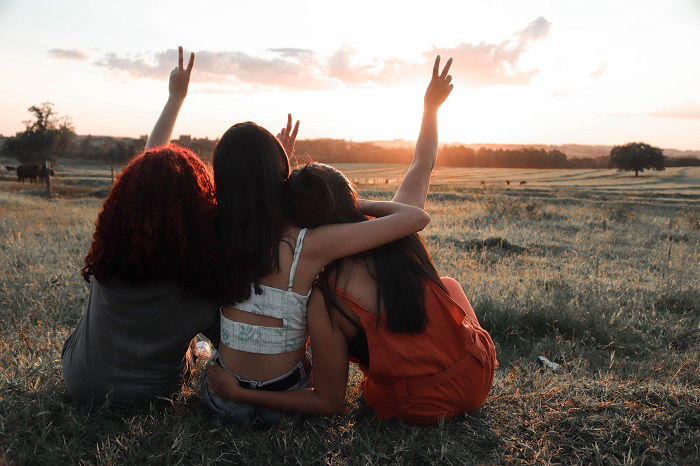 Three Girls sitting together facing away from the camera a sisters photoshoot idea