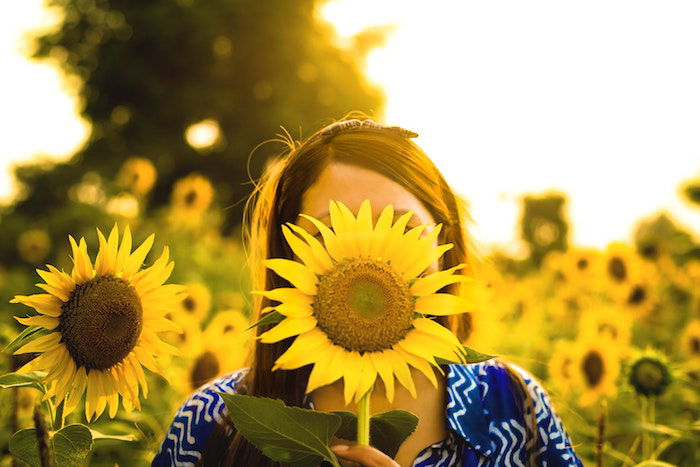 An example of one of the sunflower photoshoot ideas—a sunflower covering a person's face 