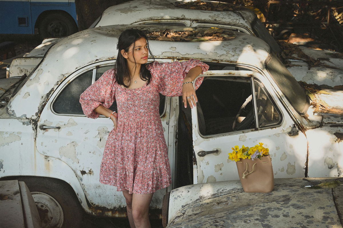 A portrait of a women standing by a car with a vintage aethetic