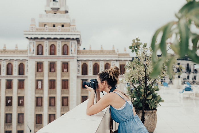 A female travel photographer taking a picture on a building's rooftop