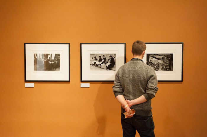 A person looking at a gallery of photos in frames wondering how to be a travel photographer