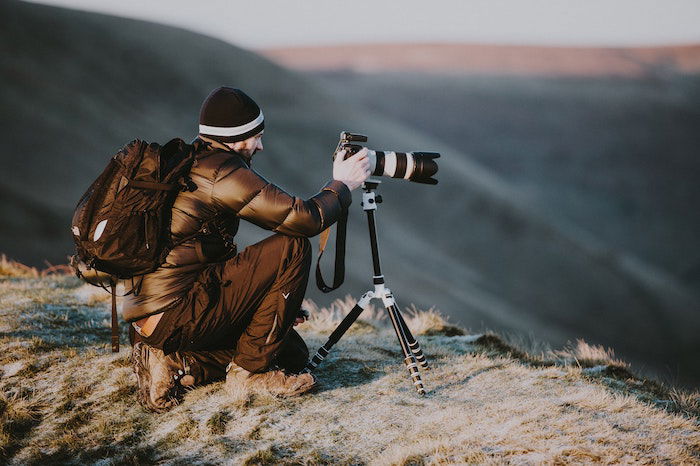 Lanscape photographer taking a picture on a ridge with a DSLR and tripod