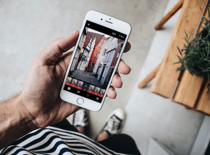 A view looking down at a person's hand holding a smartphone with a picture of quaint small town buildings