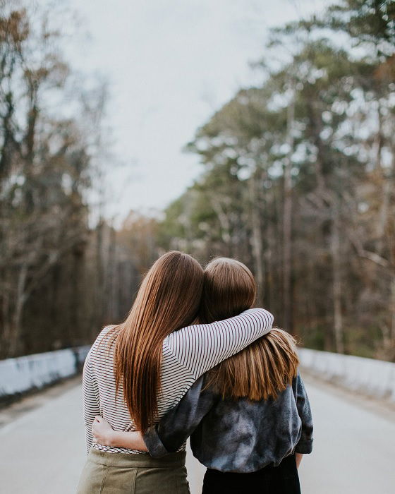 Two girls linked by arm looking away from camera as an idea for a best friend photoshoot