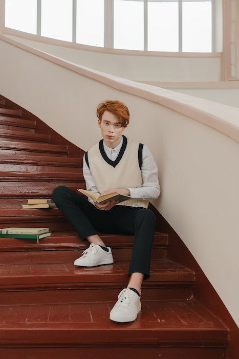 man sitting on stairs with books as an idea for male poses