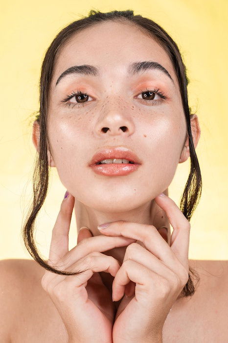 Headshot of a woman in a studio with yellow backdrop as an example of model poses